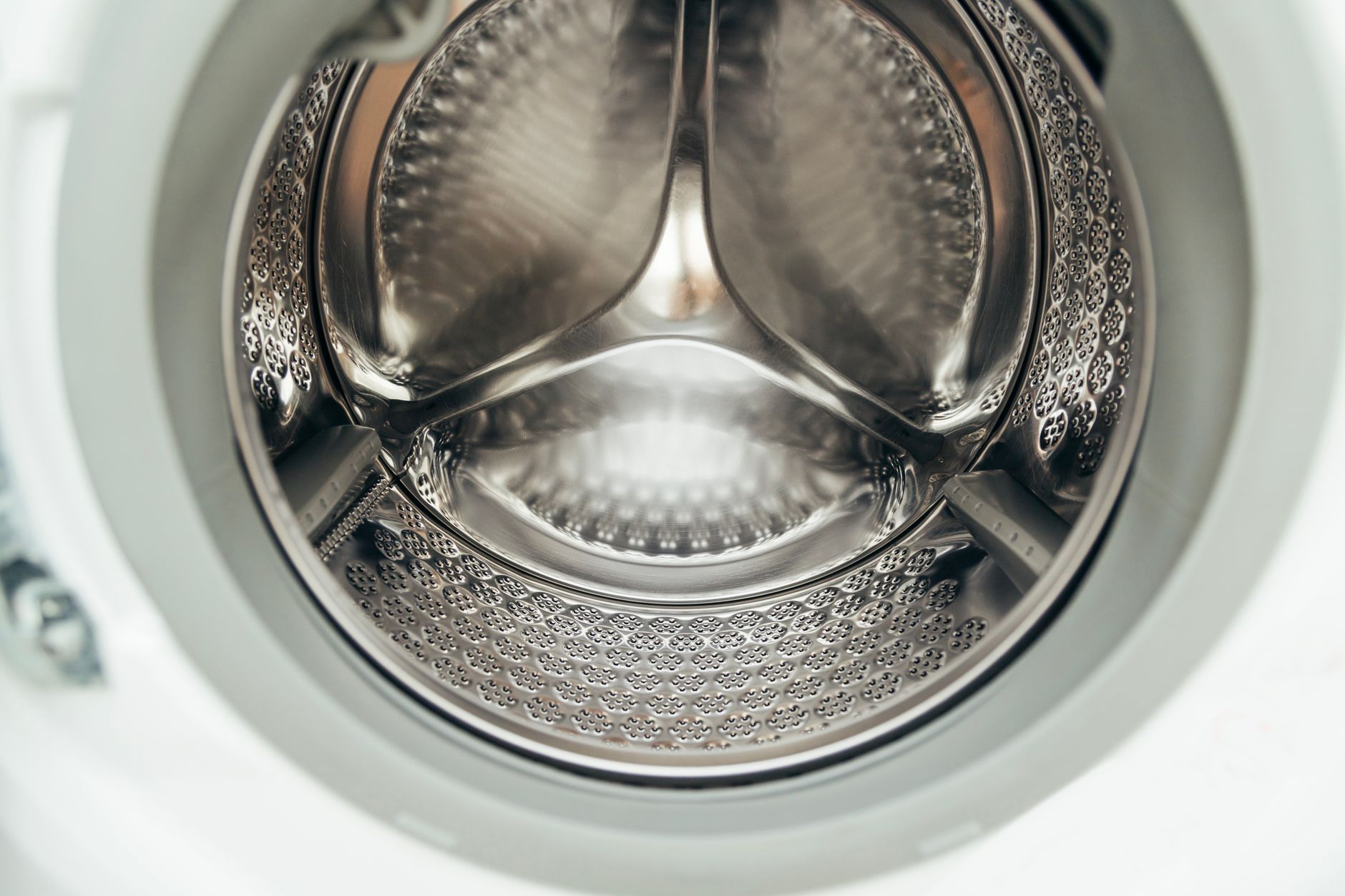 Looking into the empty stainless steel drum of a white front loader washing machine
